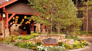 Un chalet à la façade en pierre, avec des poutres en bois et une enseigne indiquant « The Ritz Carlton Club ».