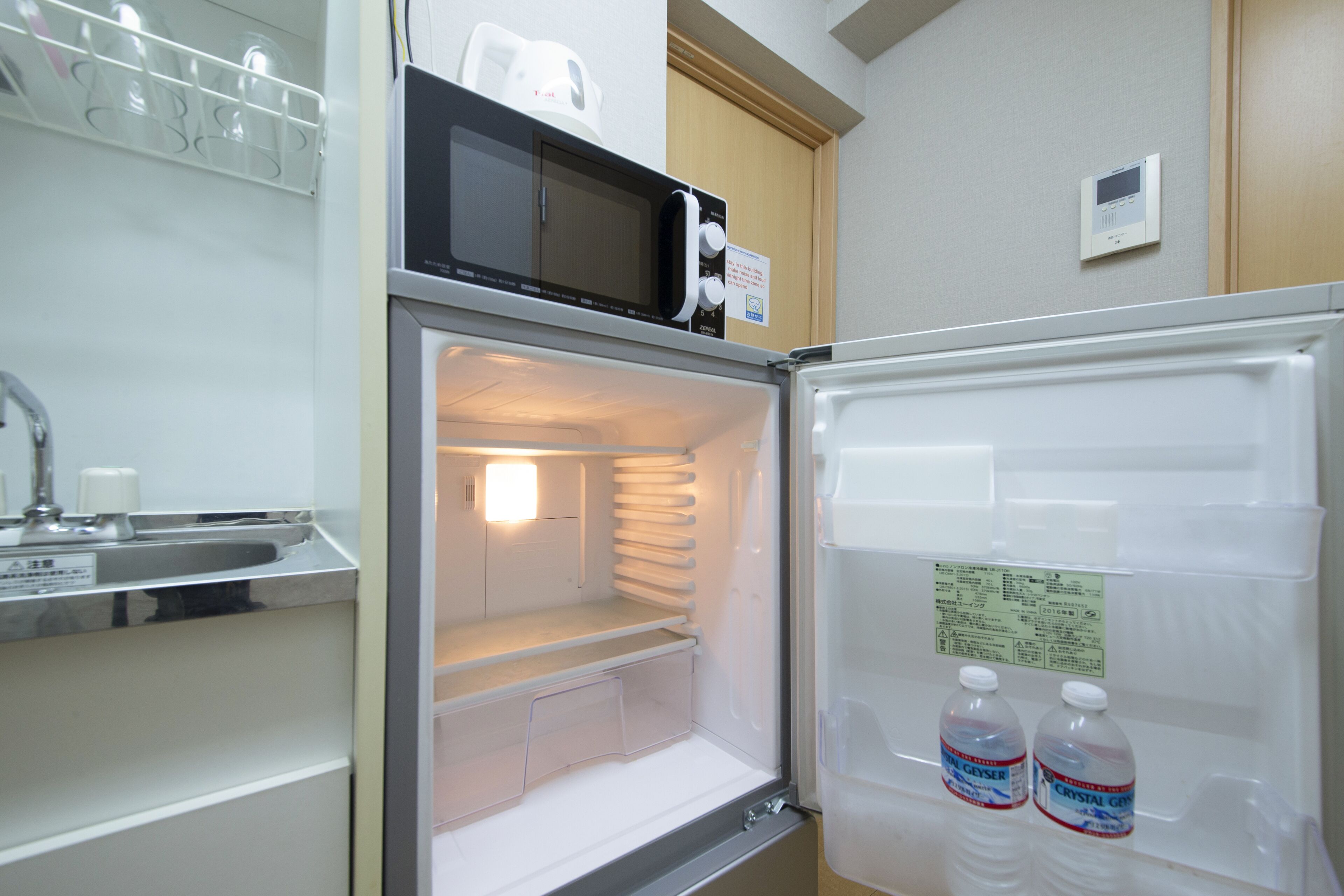 A compact kitchen with a microwave, a refrigerator, and a small sink.