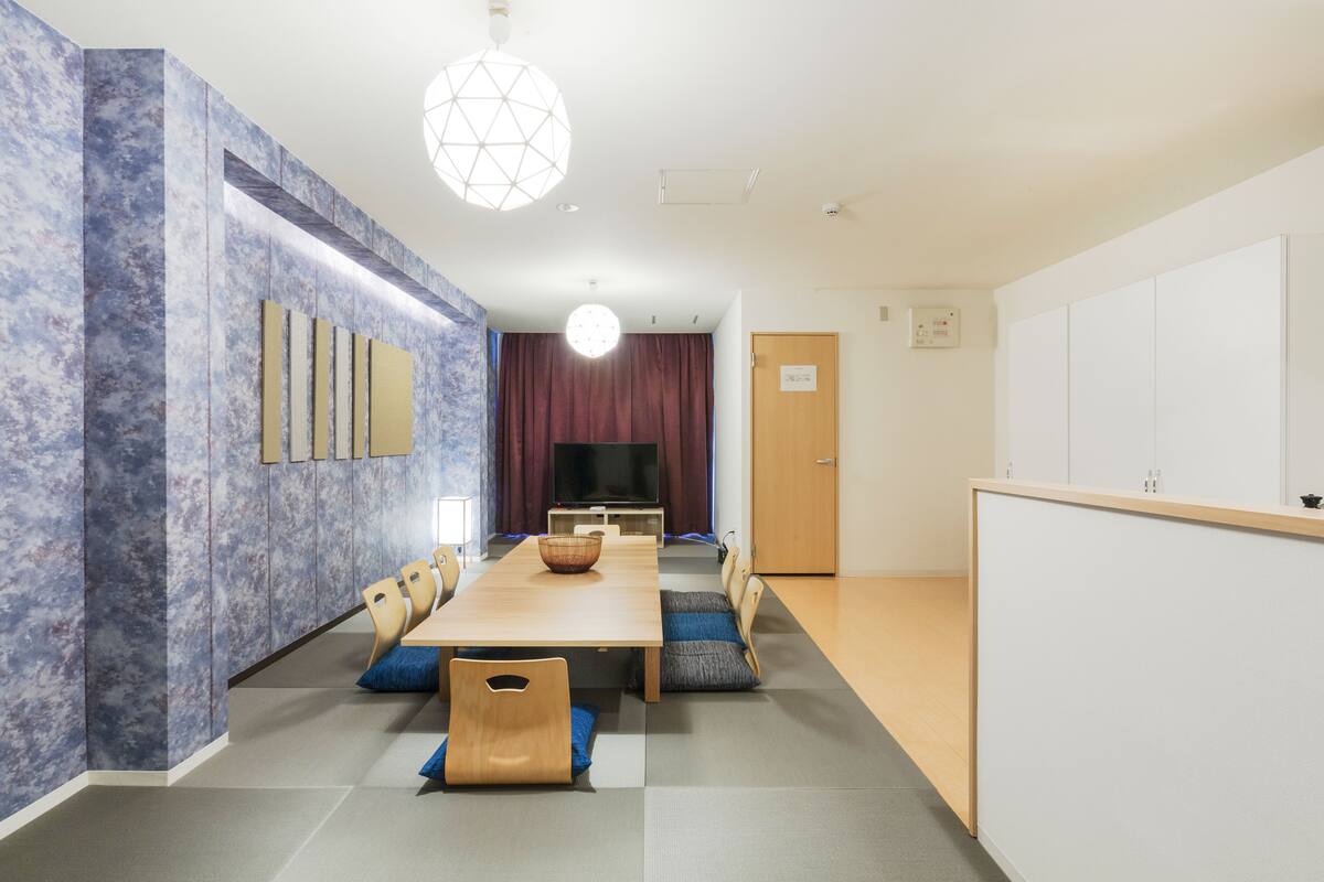 A modern conference room with a long table, chairs, a television, and a decorative light fixture.