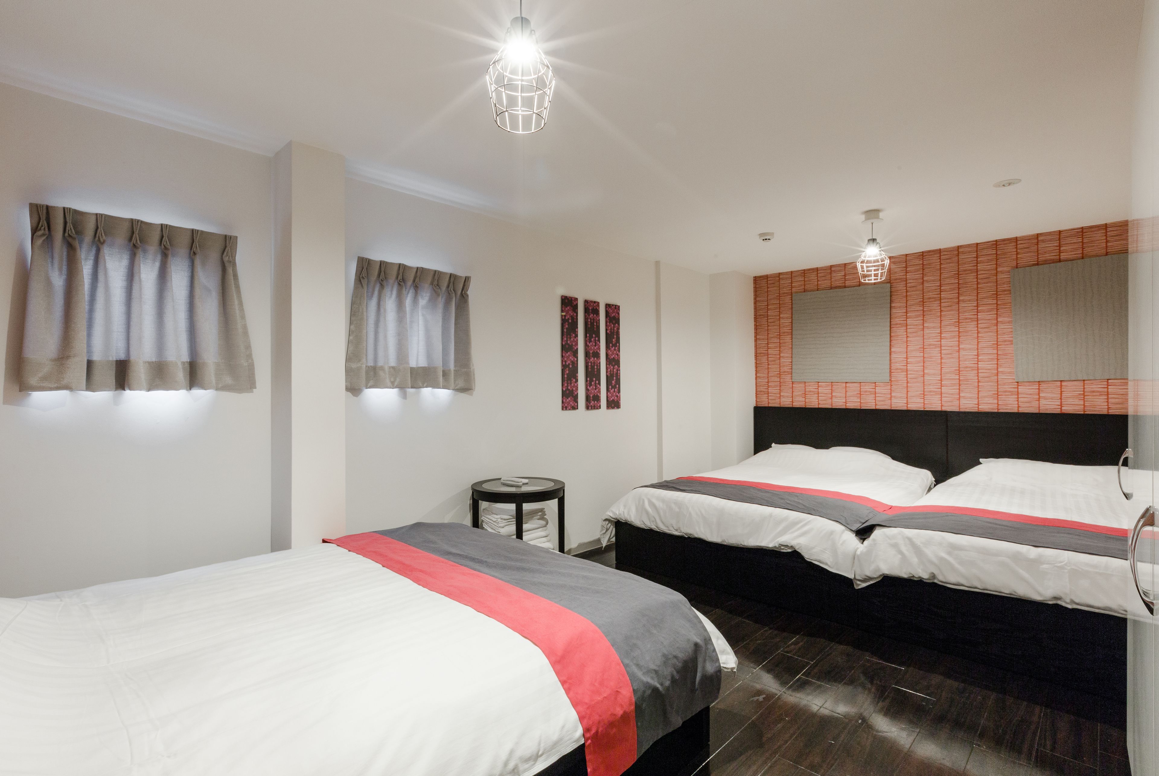 Une chambre d’hôtel avec deux lits, une table ronde et un miroir fixé au mur.