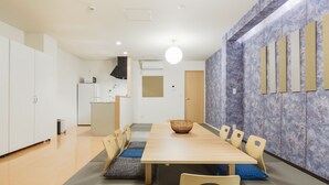 A modern dining area with a wooden table, cushioned chairs, and a decorative wall. - Crice Hotel (Osaka)