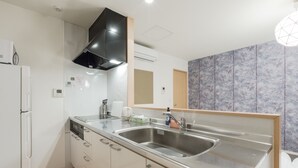 A modern kitchen with stainless steel appliances, a double sink, and a built-in oven. - Crice Hotel (Osaka)
