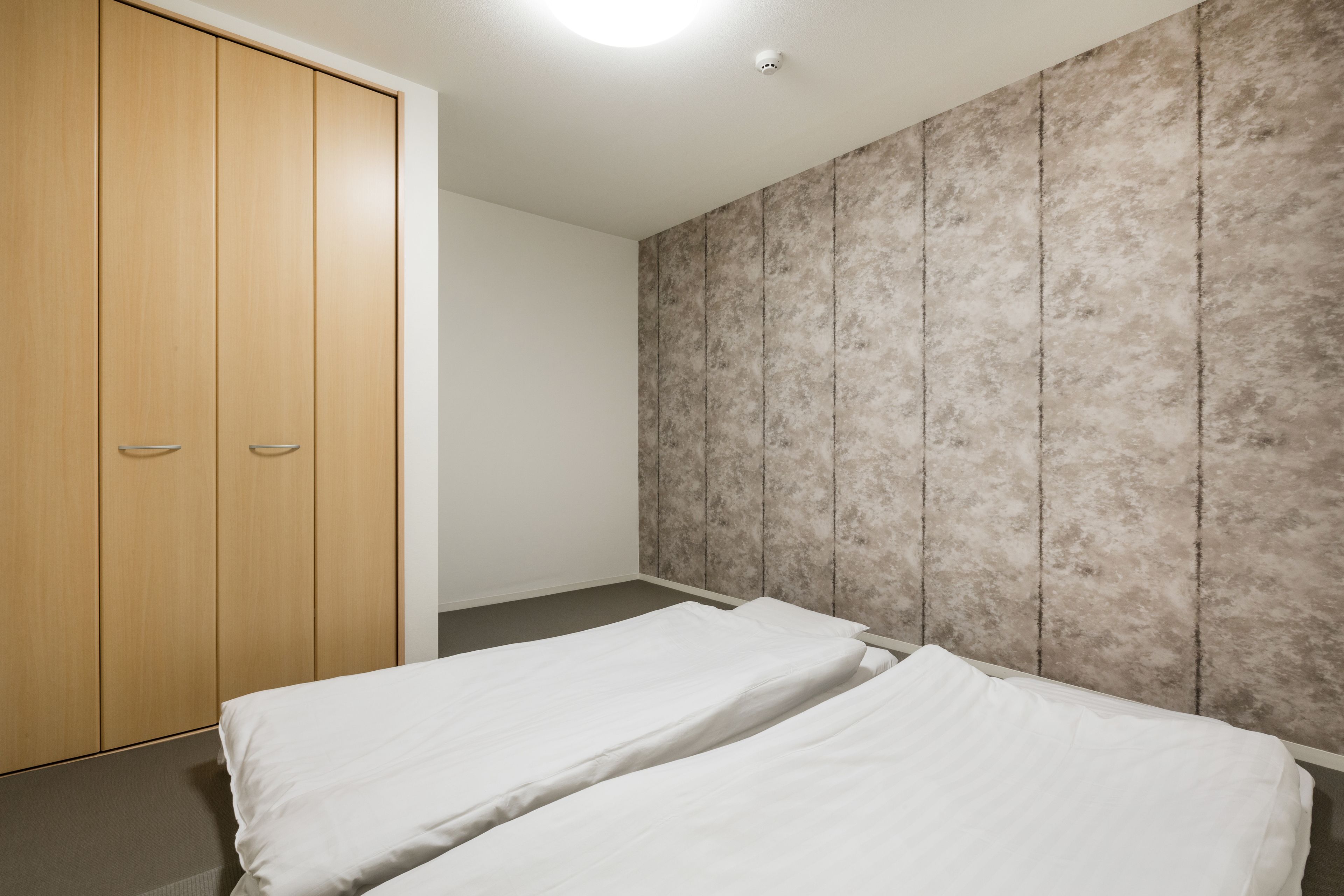 Ein Schlafzimmer mit zwei Einzelbetten, einem Holzschrank und einer strukturierten Wand.