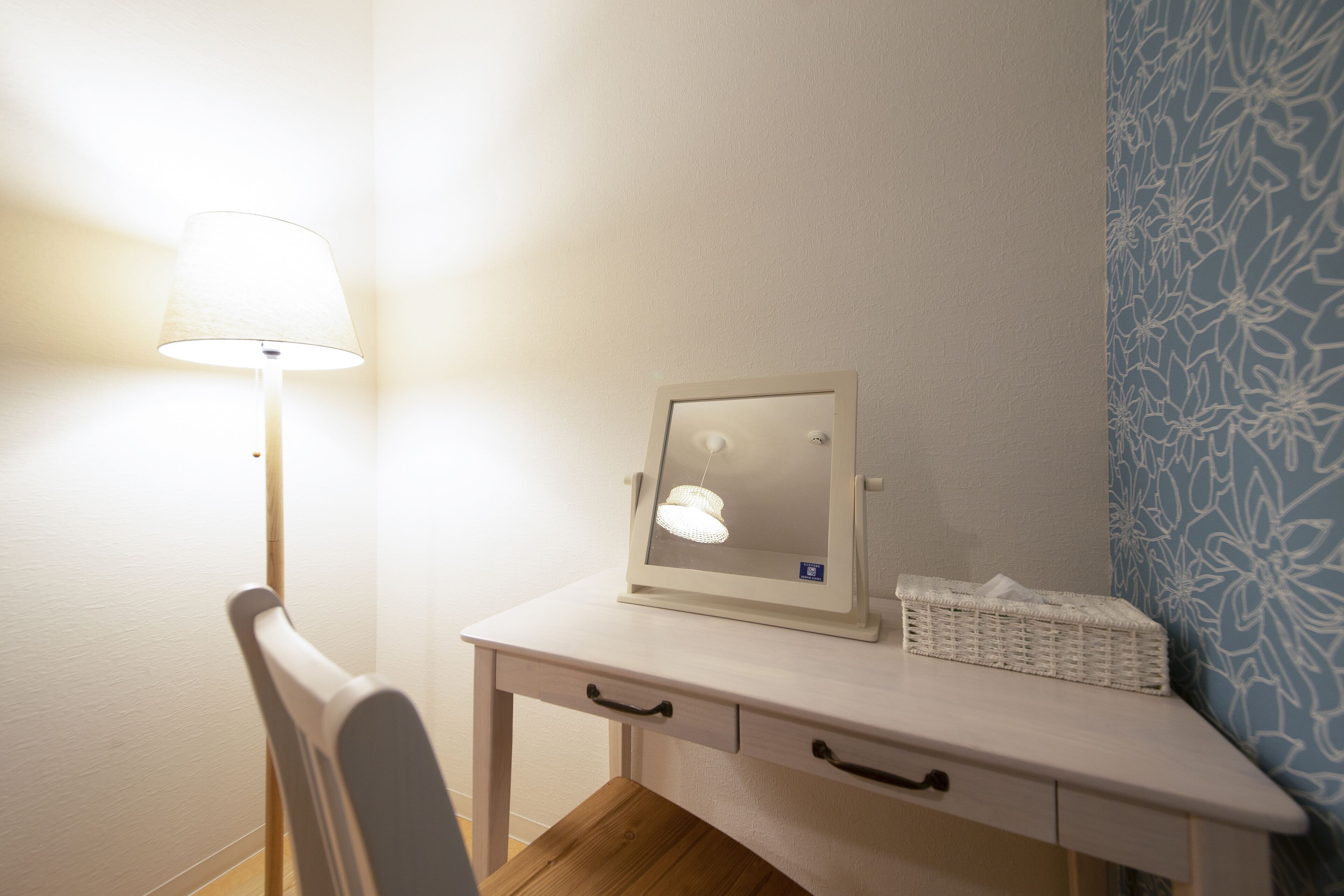 A room with a desk, a lamp, a mirror, and a patterned wall.