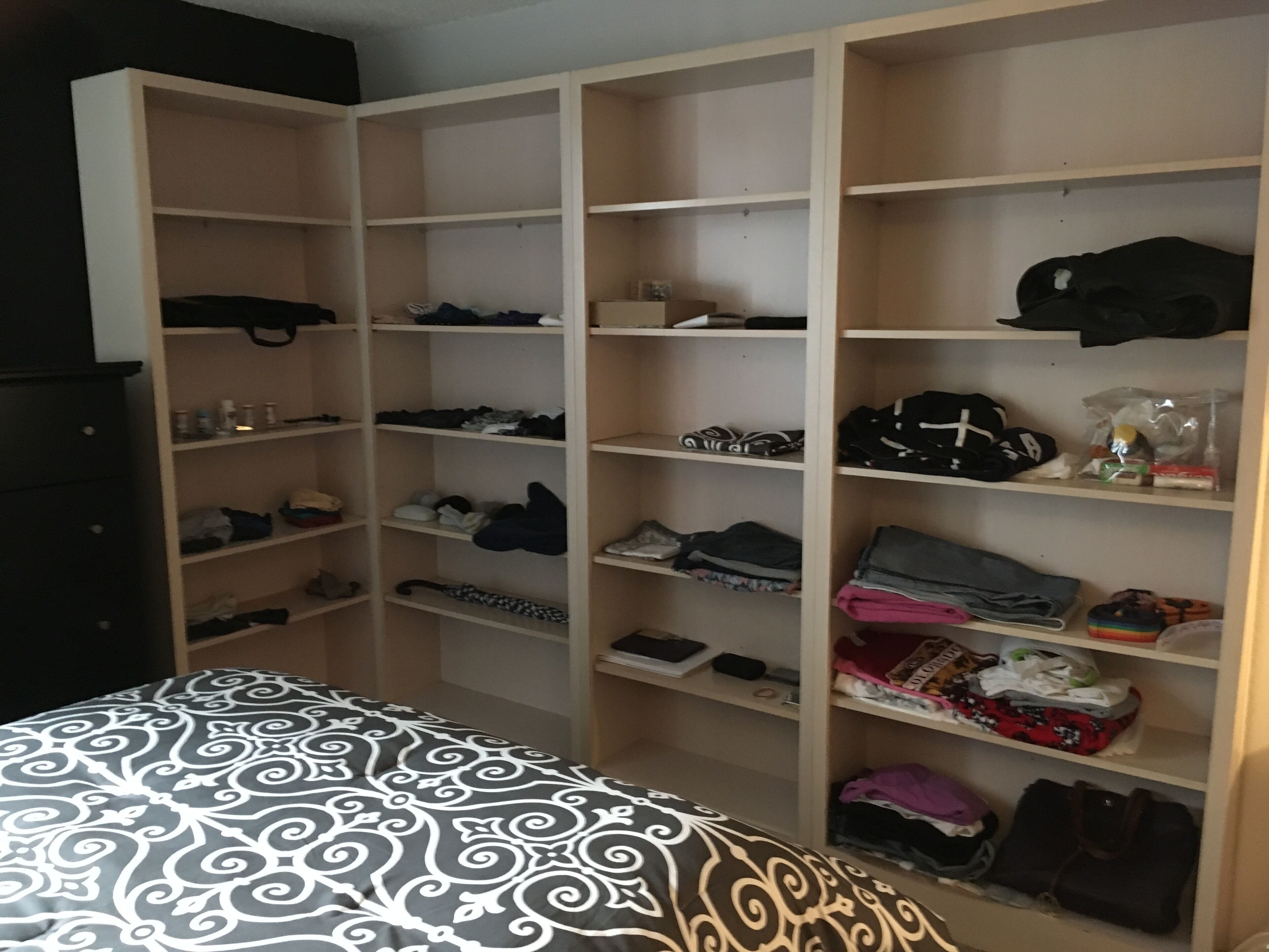 Une chambre à coucher comprenant un lit, une armoire avec plusieurs étagères et une commode.