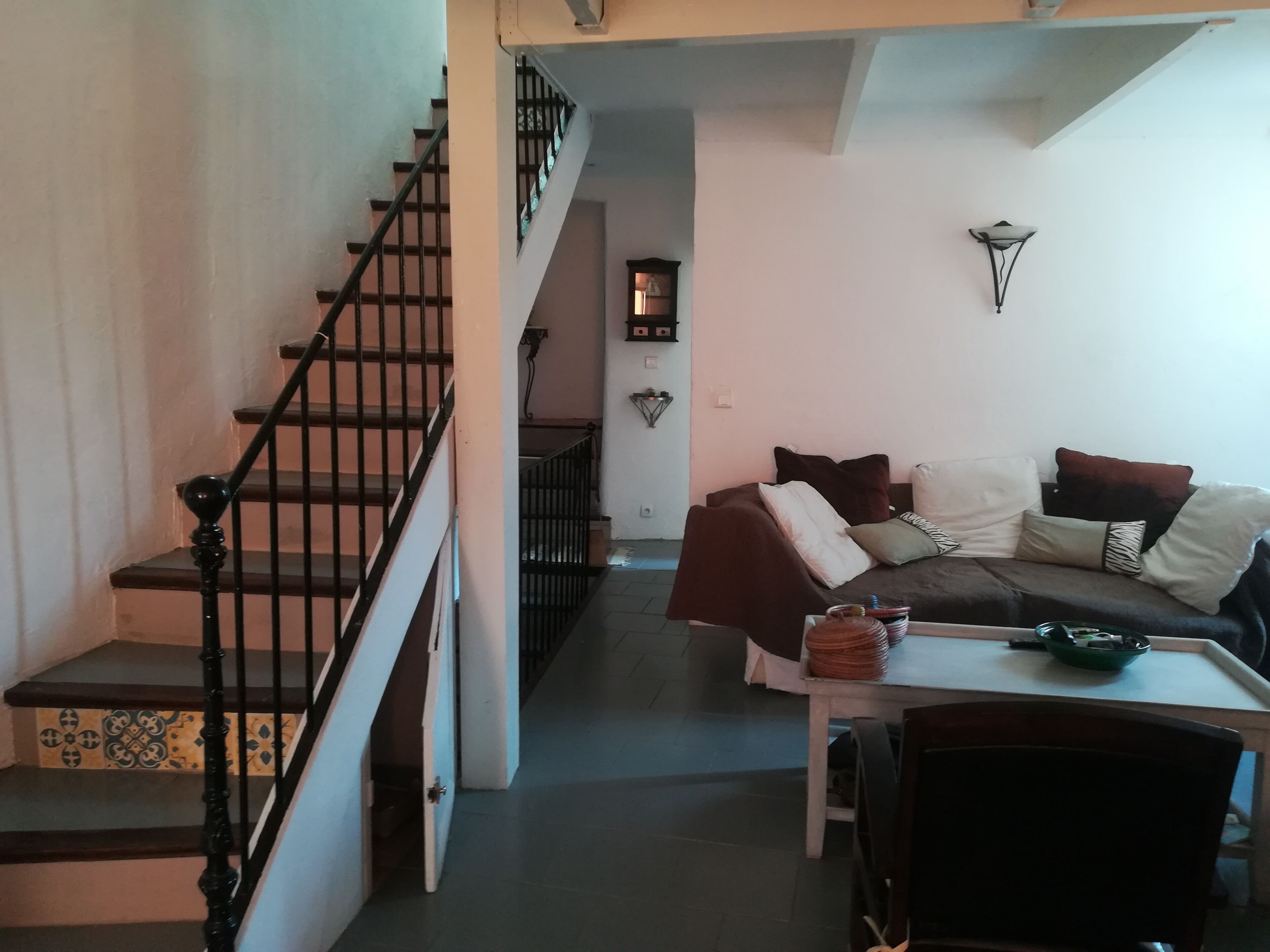A living room with a staircase, a sofa set, and a dining table.