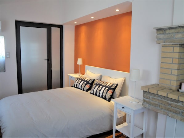 A neatly arranged bedroom with a bed, bedside tables, and a brick fireplace.