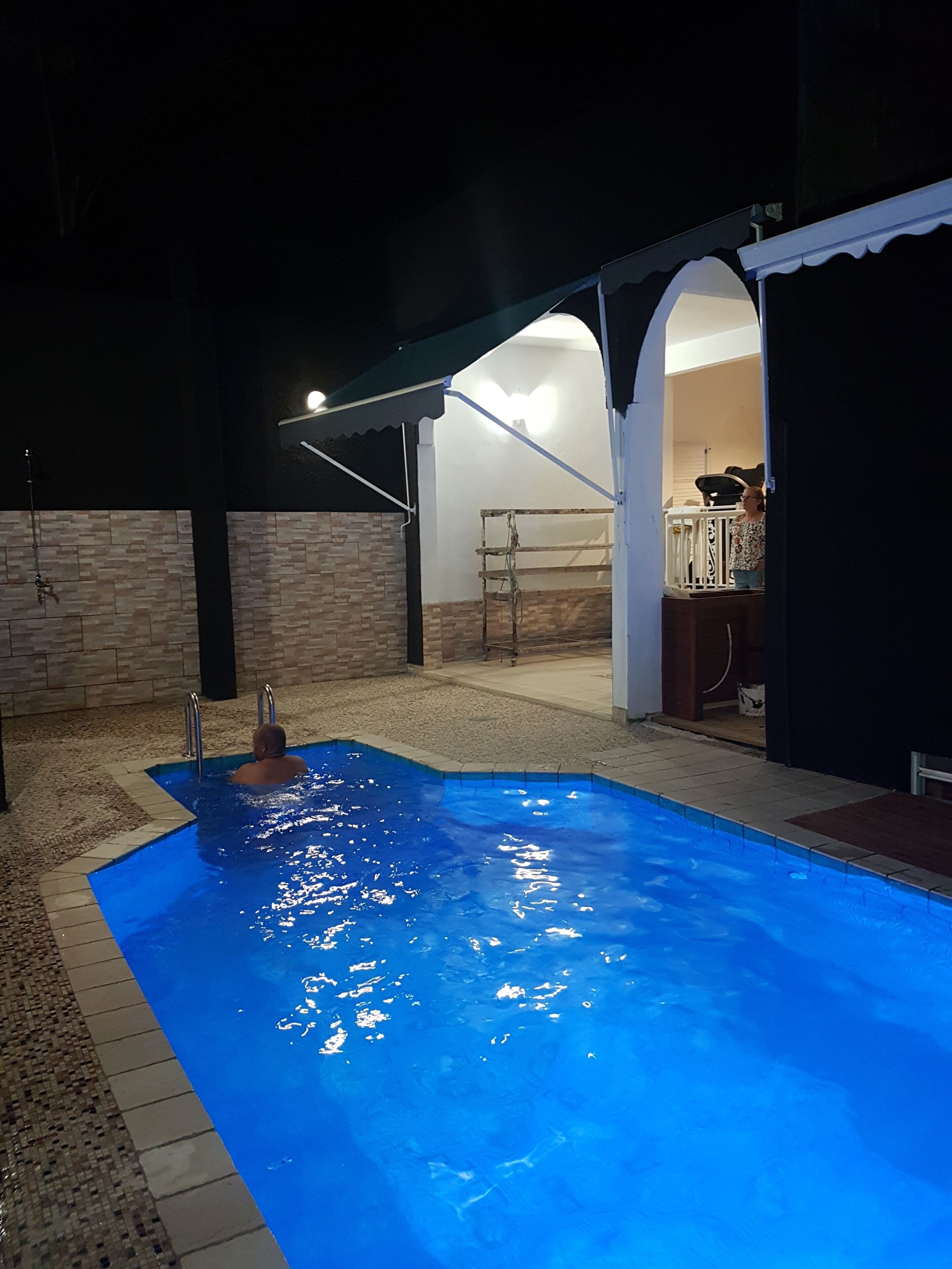A swimming pool with a tiled edge, a ladder, and a person in the water.
