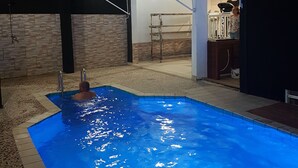 Una piscina amb vora de rajola, una escala i una persona a l'aigua.