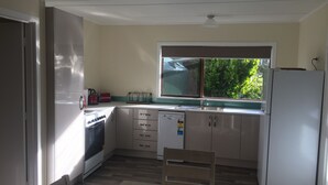 Een kleine keuken met een raam, een koelkast, een fornuis en een vaatwasser.