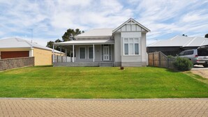 Une maison à deux étages avec un porche abrité, un garage et une pelouse bien entretenue.