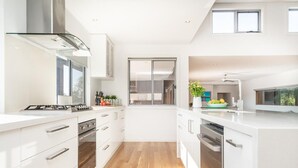 A modern kitchen with white cabinetry, stainless steel appliances, and a wooden floor. - Highview - LOVE A ROOM WITH A VIEW (Tootgarook)