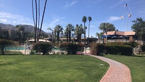 Un resort con piscina, palmeras y montañas al fondo.