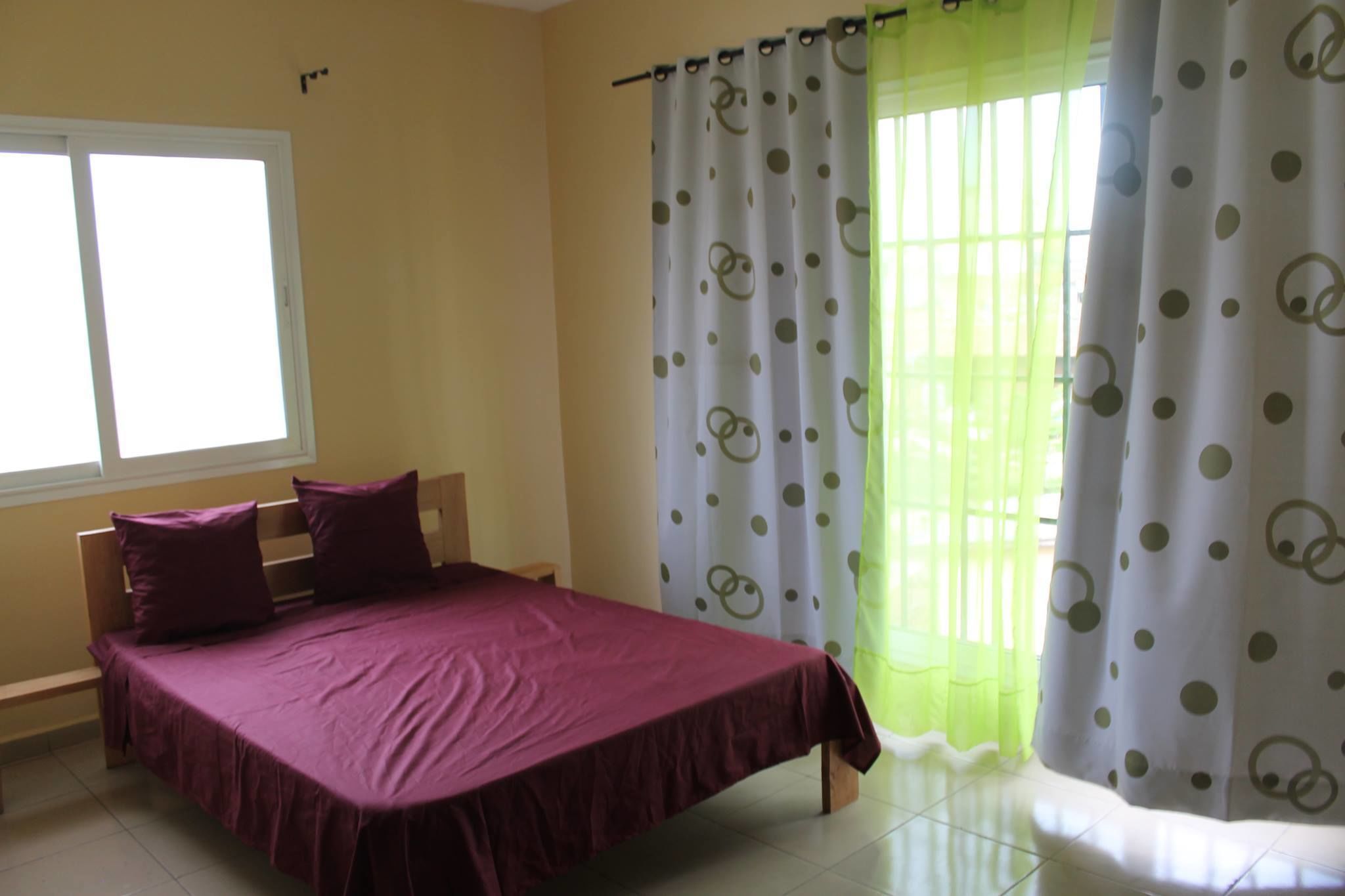 A bedroom with a bed, a window, and curtains.