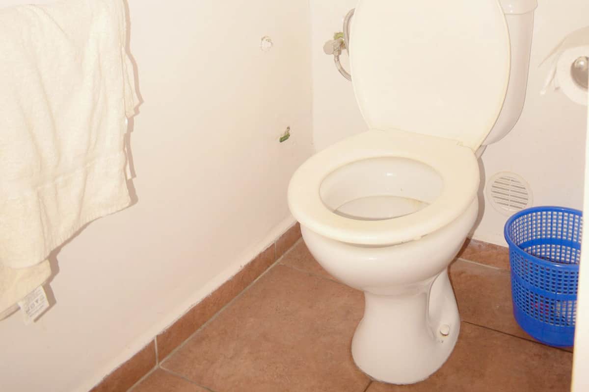 A small, clean bathroom with a toilet, a towel hanging on the wall, and a blue basket.