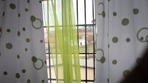 Janela com vista para área residencial, apresentando uma varanda com guarda-corpo.