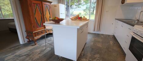 A kitchen with a central island, a built-in oven, and a window with curtains.