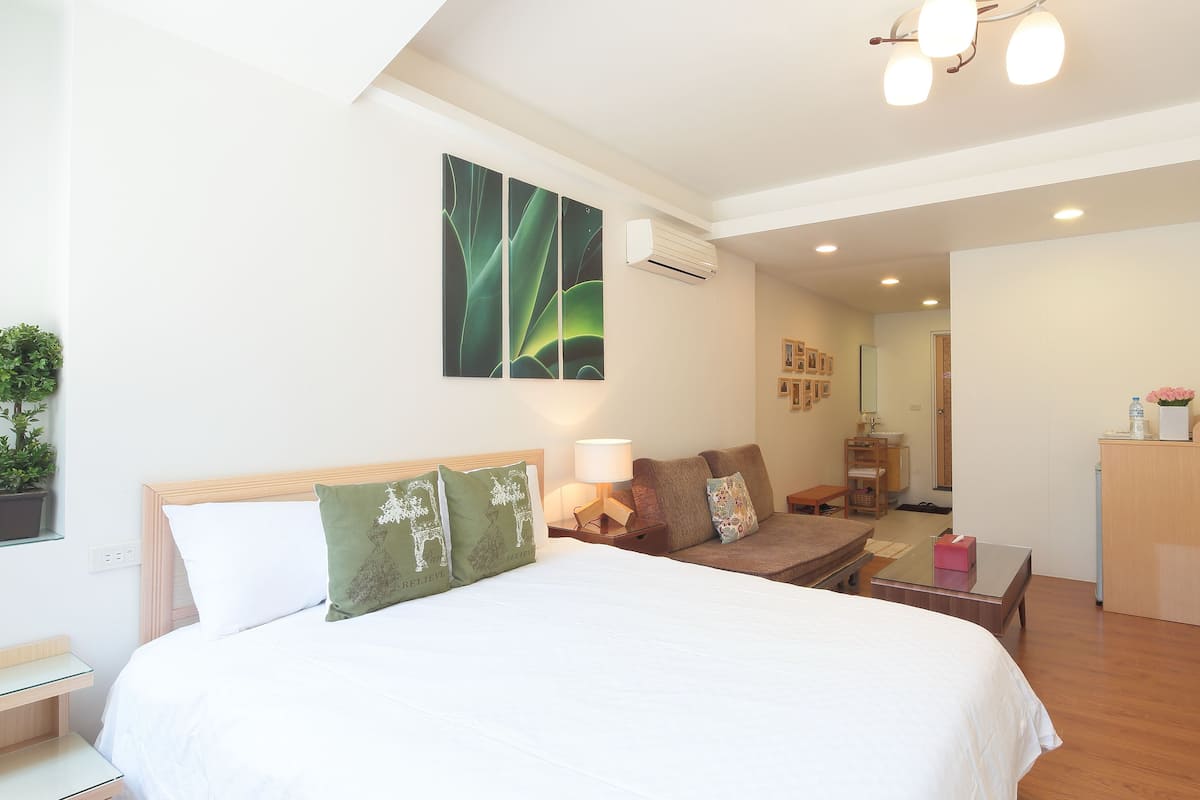 A hotel room with a bed, a sofa, a desk, and a bathroom.