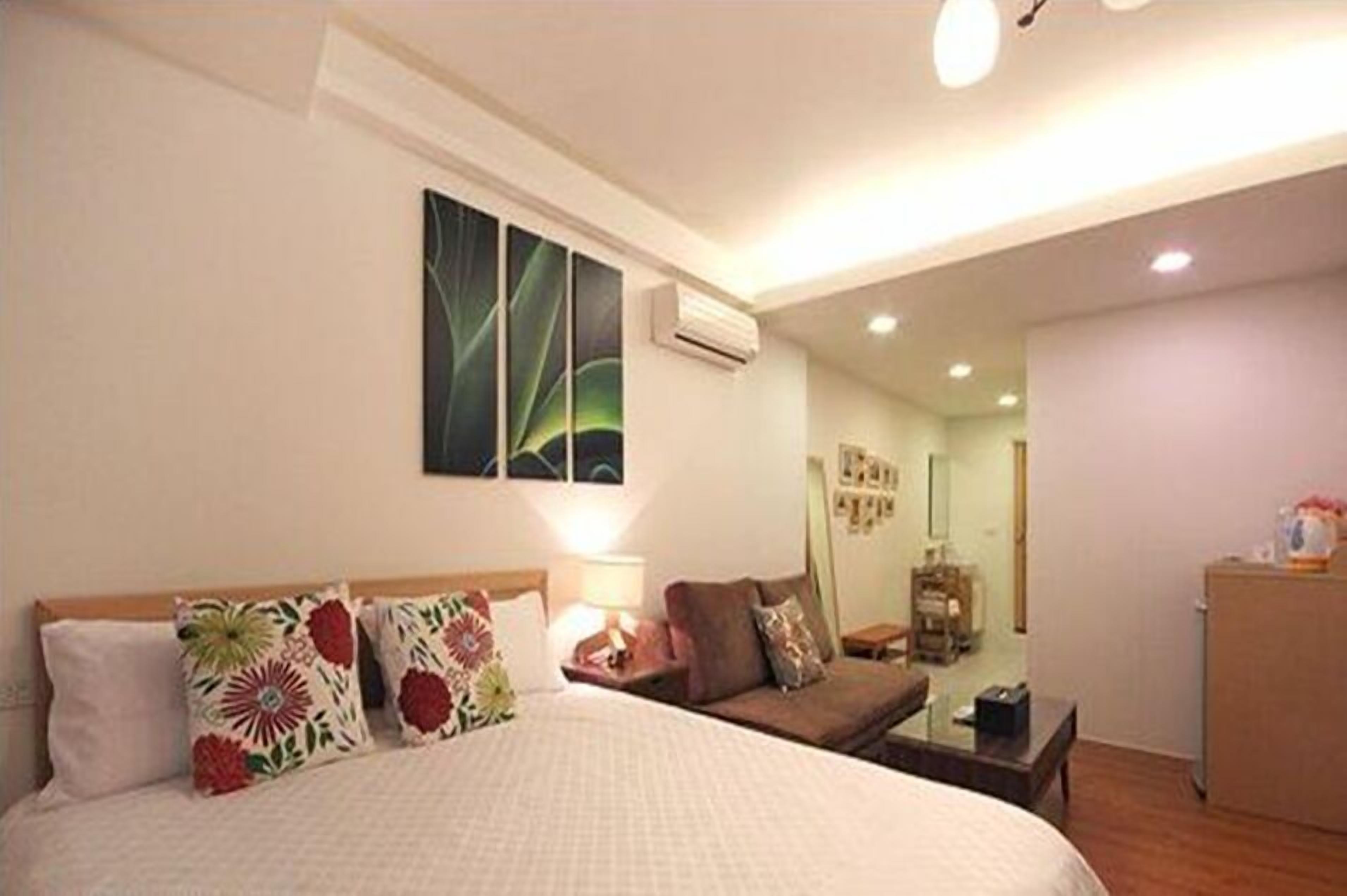A hotel room with a bed, a sofa, a desk, and a mirror.