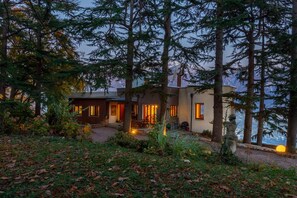Escape to a serene forest retreat with a house surrounded by tall trees and a beautifully maintained garden.