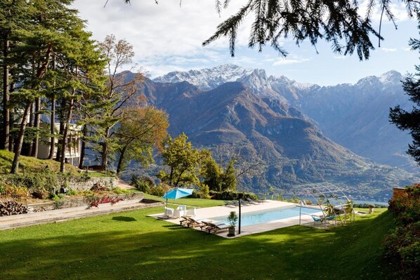 A pool area with lounge chairs and a view of snow-capped mountains.