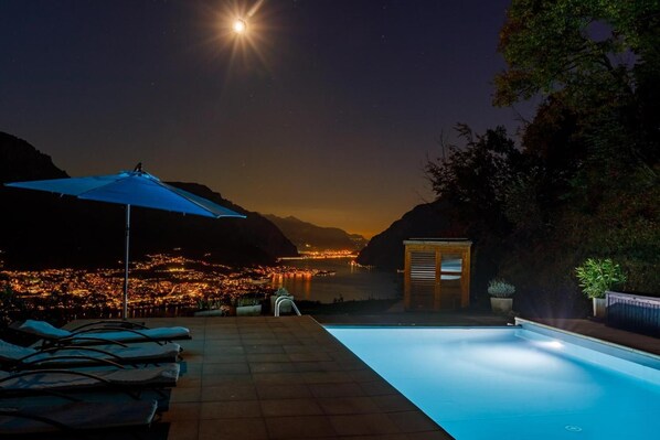 Relax by the pool surrounded by lush greenery and a stunning city view.