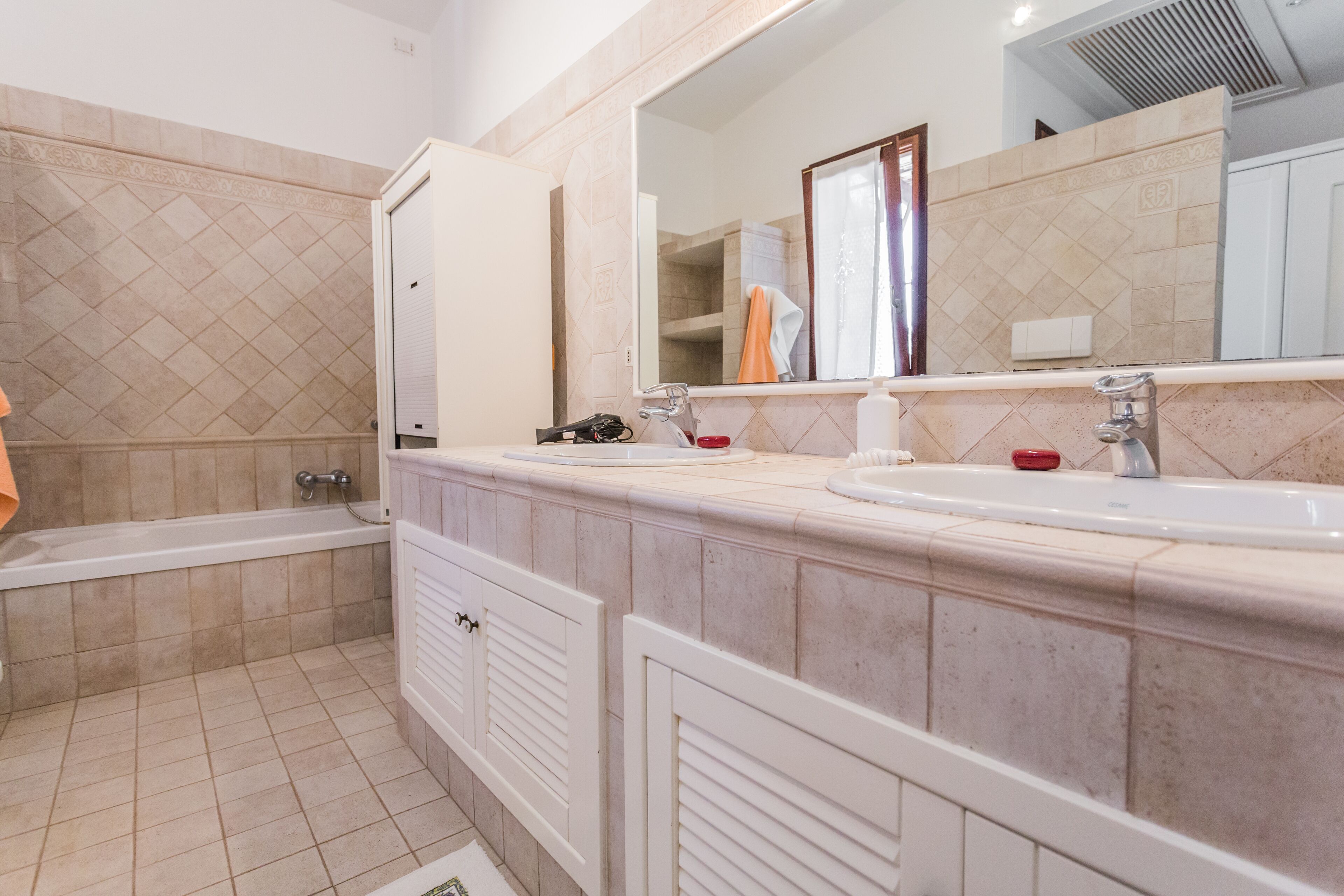 A bathroom with a bathtub, two sinks, a mirror, and a towel rack.