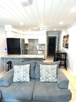 A modern kitchen with white cabinets, a black refrigerator, and a granite countertop. - Clean Beautifully Remodeled Beachfront Condo (Myrtle Beach)