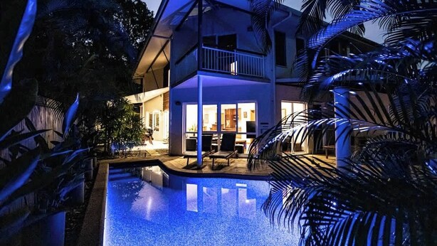 Una casa de dos pisos con piscina, un balcón e interiores luminosos.