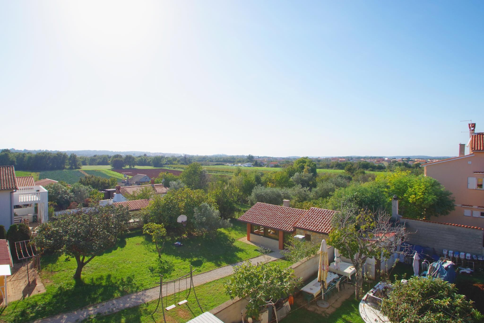 Un quartier résidentiel avec des maisons, un jardin et un ciel dégagé.