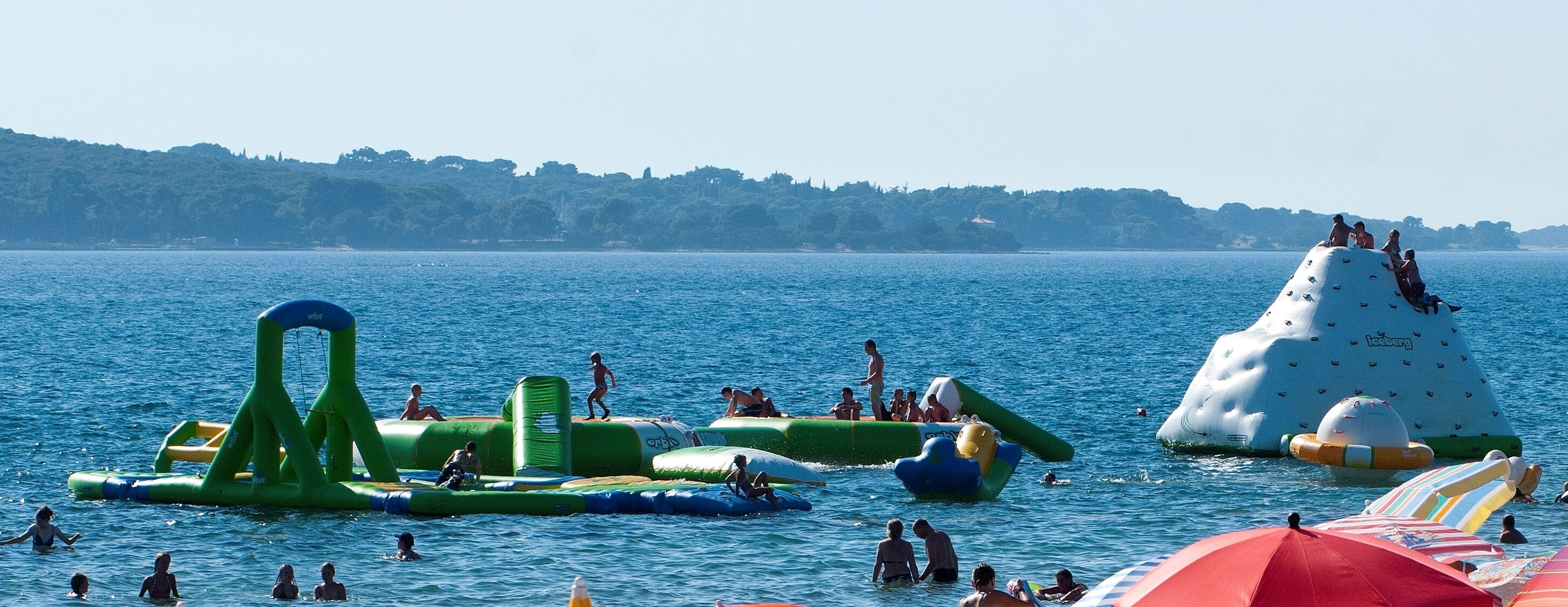 A beach with inflatable water structures and people swimming.