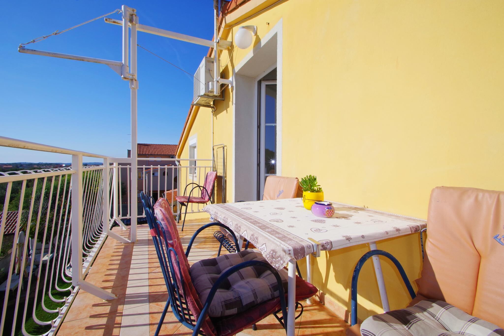 Ein Balkon mit Tisch, Stühlen und einer Topfpflanze.