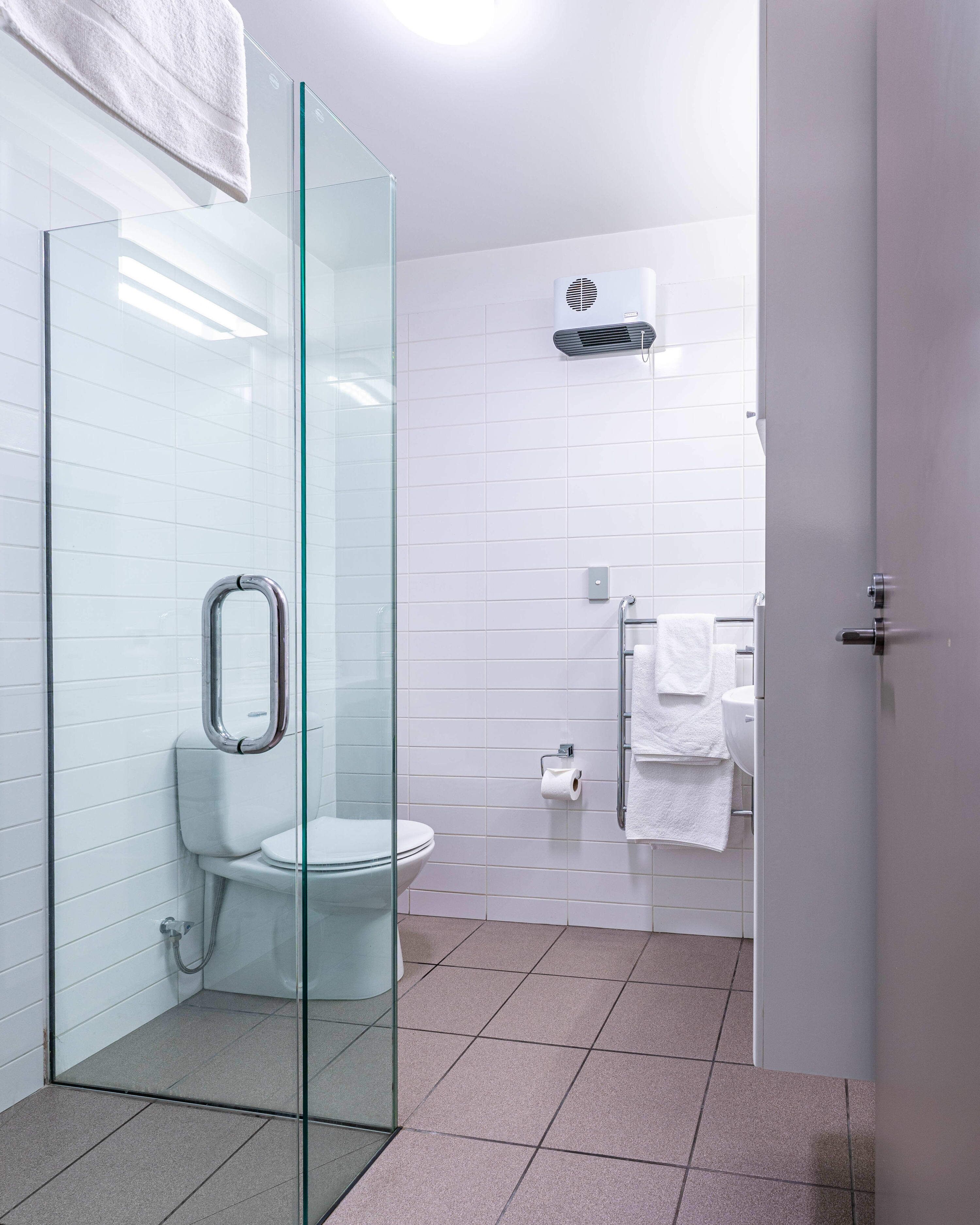 A modern bathroom with a glass shower enclosure, a toilet, and a sink with a towel rack.