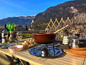 Ett bord med ett portabelt stormkök, en kastrull och matvaror, placerat med en vacker bergskuliss i bakgrunden.