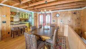 A wooden interior with a dining table, chairs, and a chandelier. - Waterfront on Crystal Lake! (Orleans)