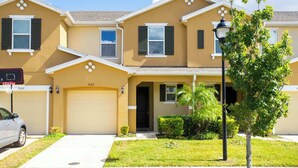 A two-story residential building with a garage, a basketball hoop, and a well-maintained lawn. - Four Bedrooms TownHome Close to Disney 5162A (Kissimmee)