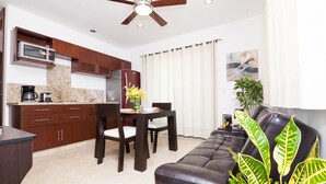 Cozinha moderna com armários de madeira escura, micro-ondas e área de jantar com mesa e cadeiras.