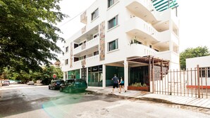 Um edifício de vários andares com entrada coberta e acesso por portão.