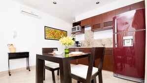 Uma cozinha moderna com uma mesa e cadeiras de madeira escura, uma geladeira vermelha e um micro-ondas sobre a bancada.