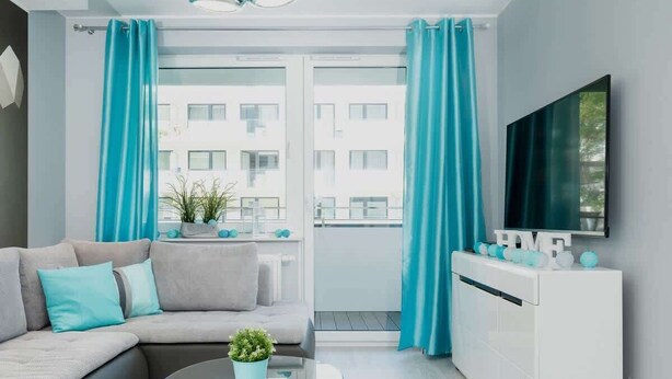 A modern living room with a sofa, a glass coffee table, and a TV mounted on the wall. - Stylish Apartment with Gym | 400 m to the Beach, Balcony (Kolobrzeg)