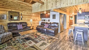 A cozy log cabin interior with a living room, kitchen, and dining area. - Dock, Sauna & Hot Tub! 'Loon Lake Lodge' (Pequot Lakes)