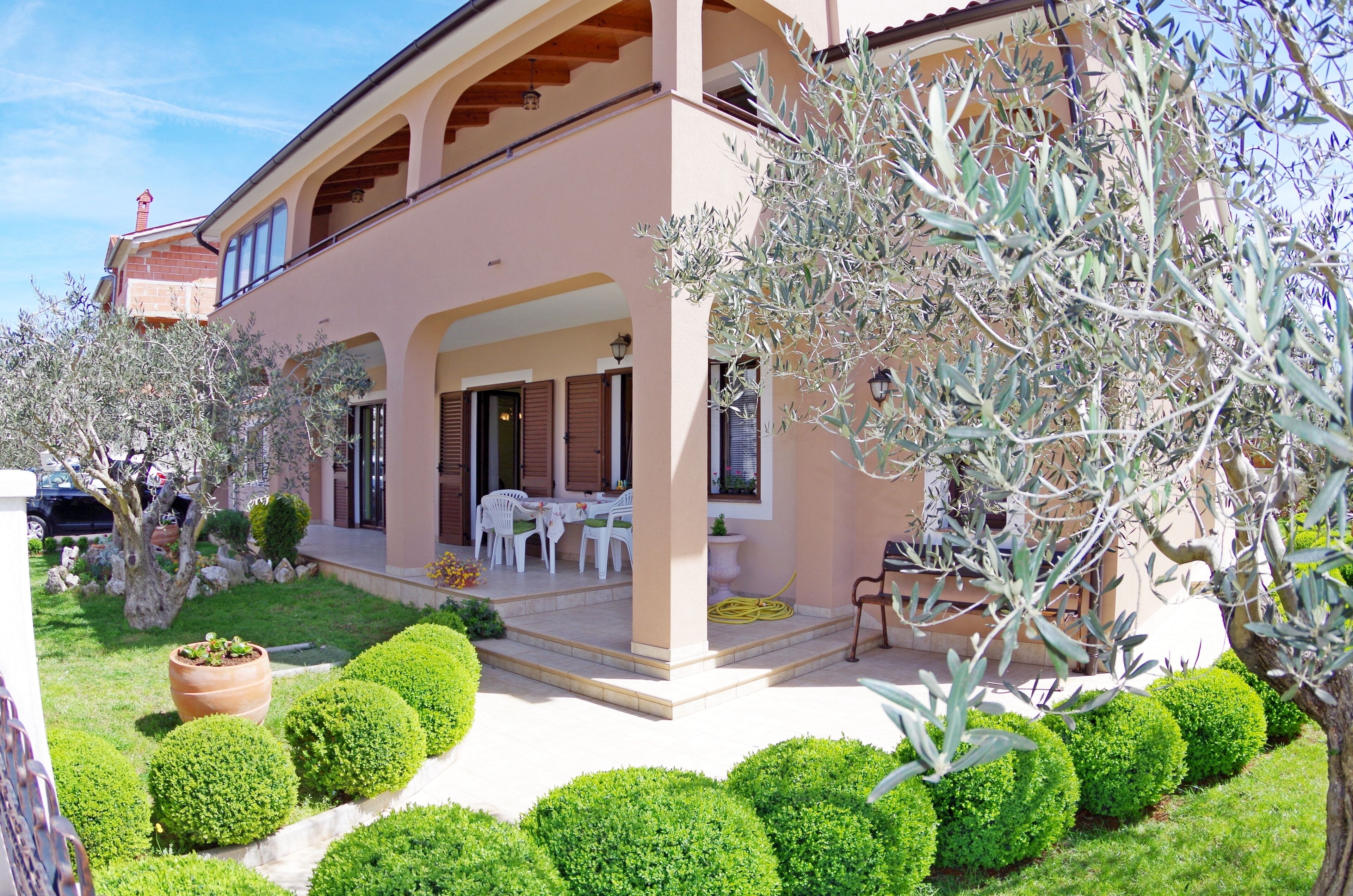 A two-story building with a covered patio, outdoor seating, and well-maintained landscaping.
