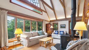 A cozy living room with a fireplace, large windows, and comfortable seating. - Private Beach and Roof Top Deck! (Orleans)