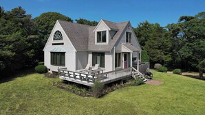 A two-story house with a covered porch, a small deck, and a well-maintained lawn. - Private Beach and Roof Top Deck! (Orleans)