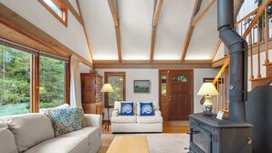 A cozy living room with a sofa, a wooden table, and a fireplace. - Private Beach and Roof Top Deck! (Orleans)
