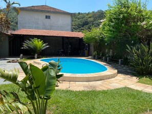 Una piscina circondata da un patio, con una casa sullo sfondo.