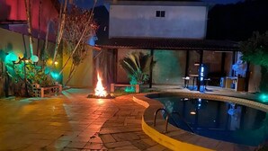 A poolside area with a fire feature, outdoor seating, and a covered patio. - HOUSE WITH POOL CANTO DO FORTE, 10 people (Praia Grande)