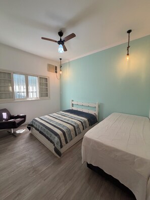 A bedroom with two beds, a ceiling fan, a window with blinds, and a chair. - HOUSE WITH POOL CANTO DO FORTE, 10 people (Praia Grande)