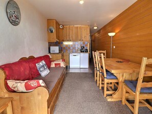 Un espacio habitable compacto con sofá, mesa de comedor y kitchenette.