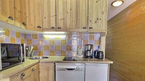 Une cuisine compacte dotée de meubles en bois, d’un lave-vaisselle, d’un four à micro-ondes et d’une machine à café.